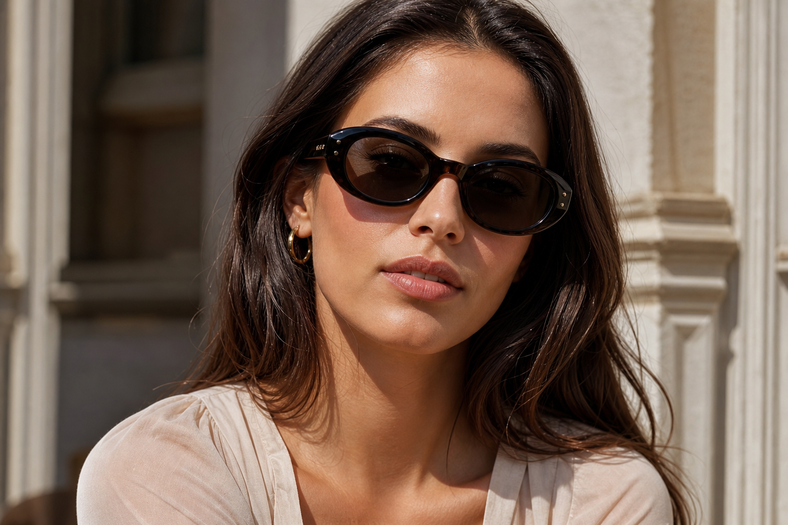 Editorial portrait for a guide to the best sunglasses for an oblong face featuring softly rounded black sunglasses